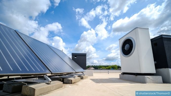 Foto einer Photovoltaikanlage auf dem Dach. Daneben steht eine Wärmepumpe