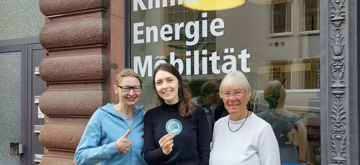 Drei Mitarbeiterinnen der Karlsruher Energie- und Klimaschutzagentur stehen vor dem Beratungszentrum und lächeln in die Kamera.