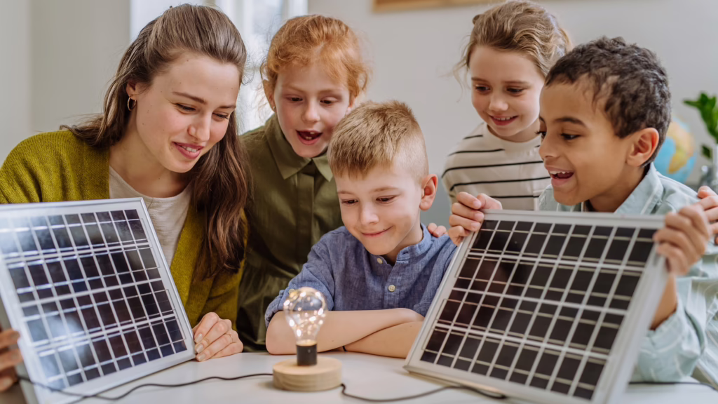 Eine Frau erklärt Kindern, wie eine Photovoltaikanlage funktioniert. Die Kinder sind erstaunt und schauen sich alles neugierig an.