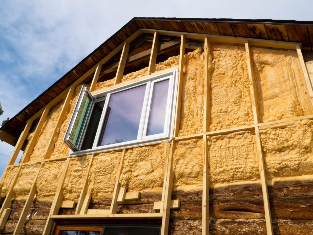 Haus von außen, das saniert wird. Ein Fenster steht offen und das Haus wird vermutlich gerade gedämmt.