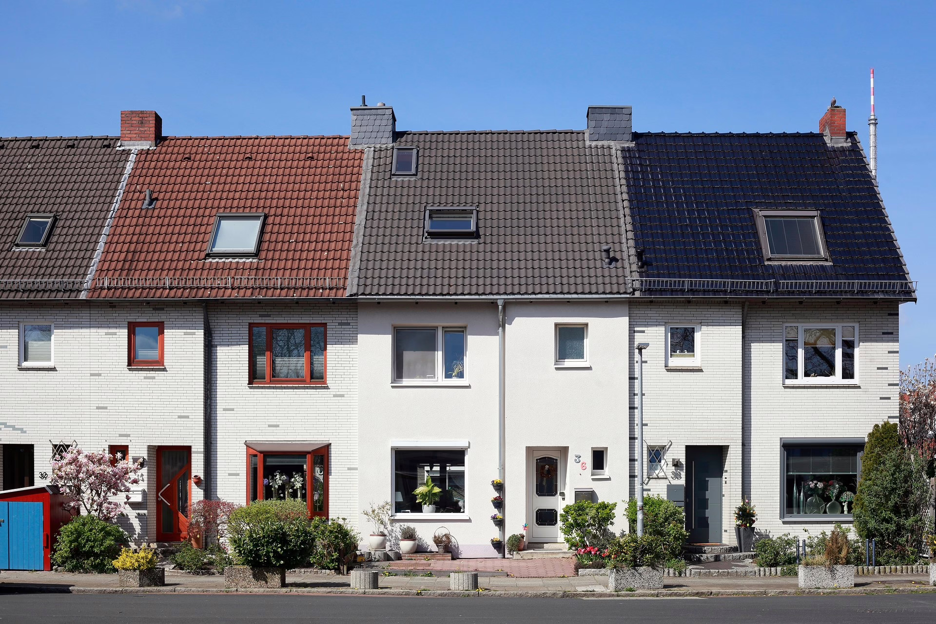 Frontalansicht einer Reihe an Einfamilienhäuser mit Vorgärten.