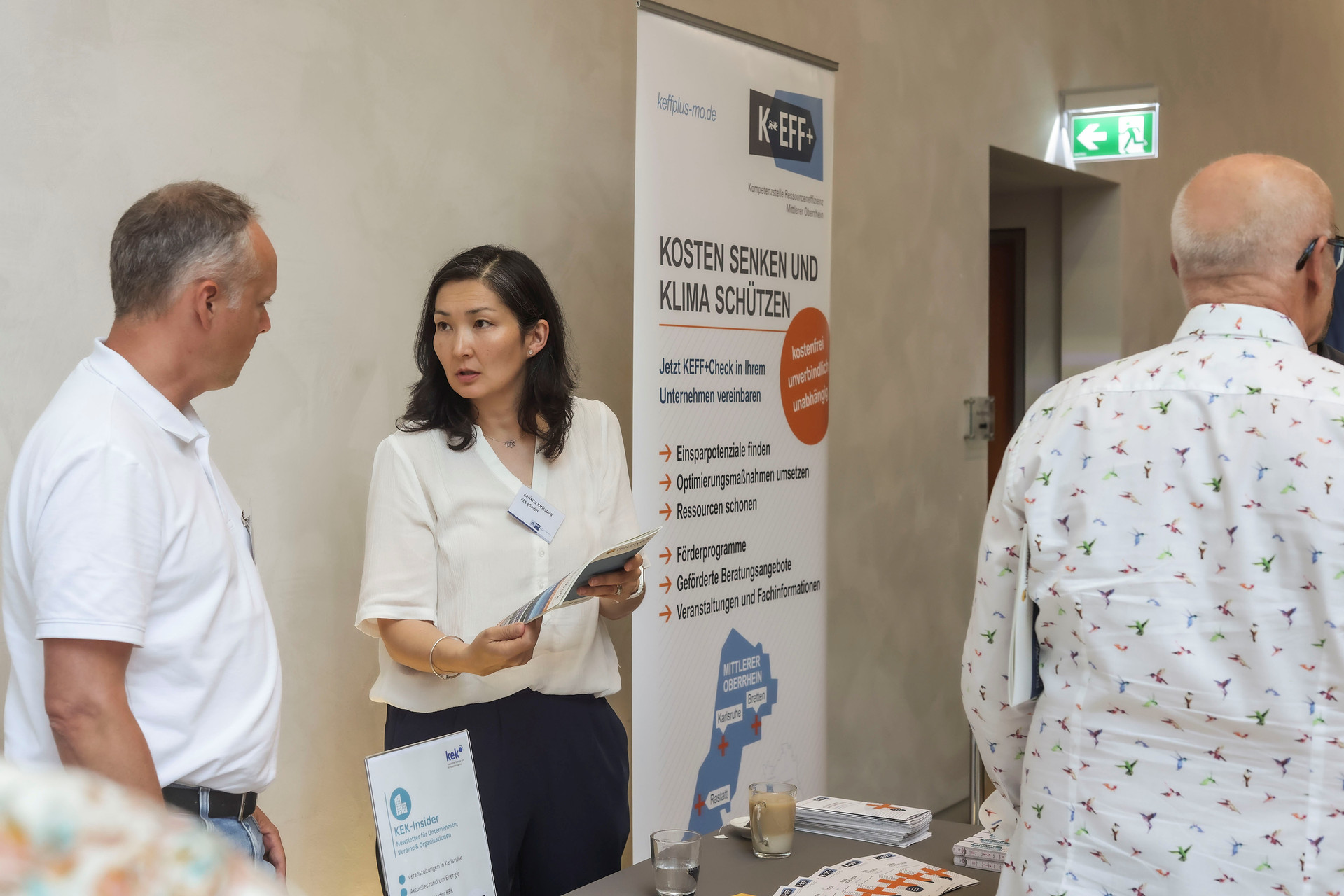 Zwei KEK Mitarbeitende betreuen einen Infostand nach der Veranstaltung.