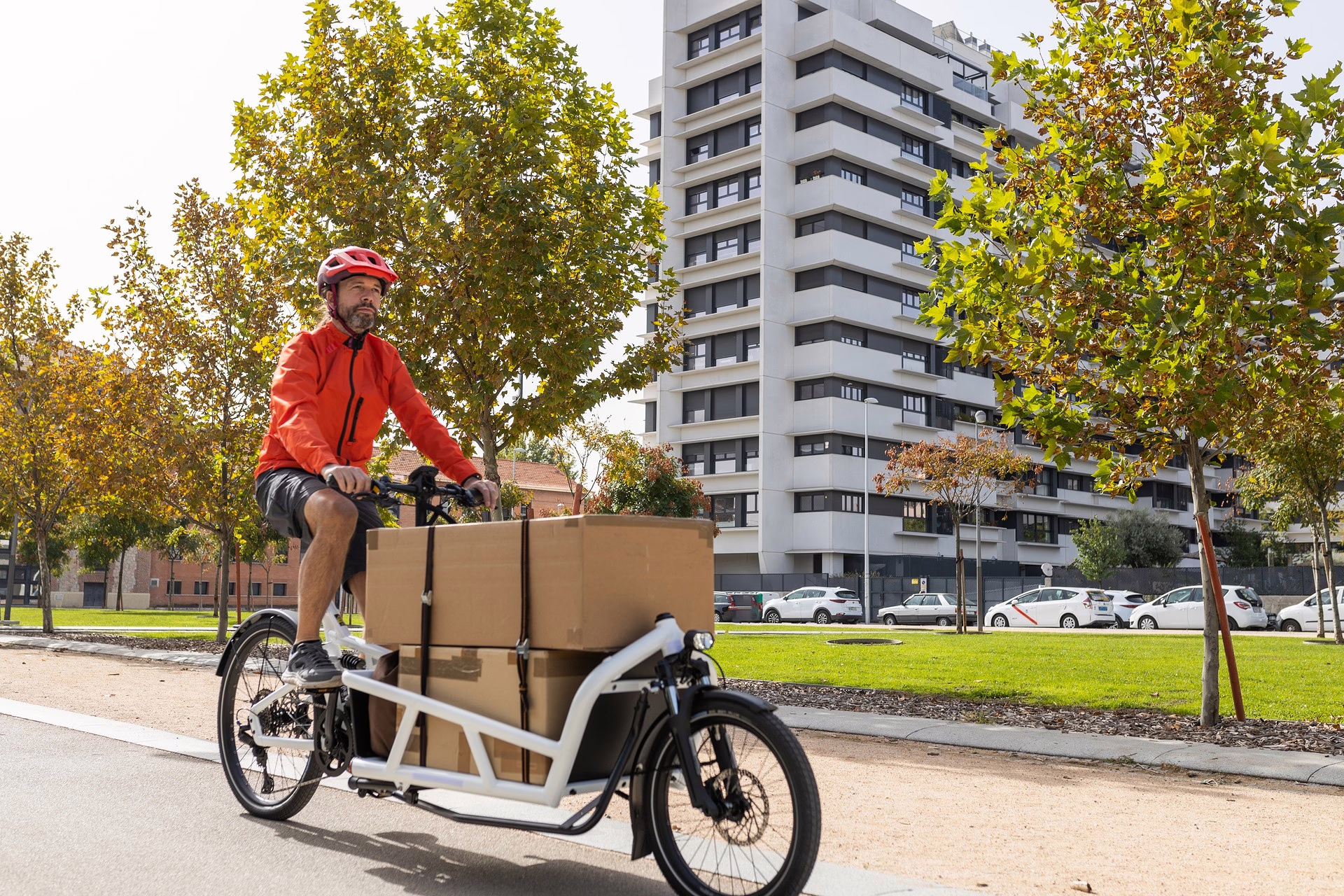 Ein Mann fährt auf einem vollgeladenen Lastenrad durch eine Stadt.