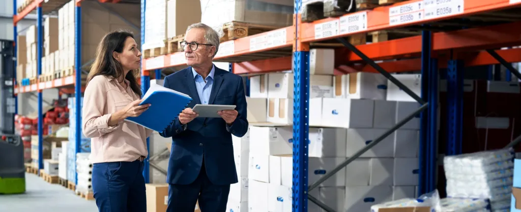 Eine Frau und ein Mann unterhaten sich in einer Lagerhalle.