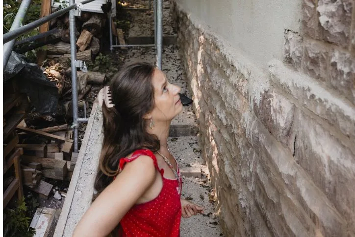 Die Hausbesitzerin Galina steht vor ihrem Haus und blickt die Fassade besorgt nach oben.