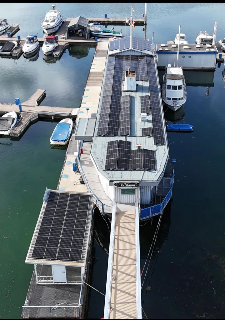 Ein längliches Motorboot ist von oben zu sehen. Auf dem Dach des Boots wurden Photovoltaikanlagen installiert. 