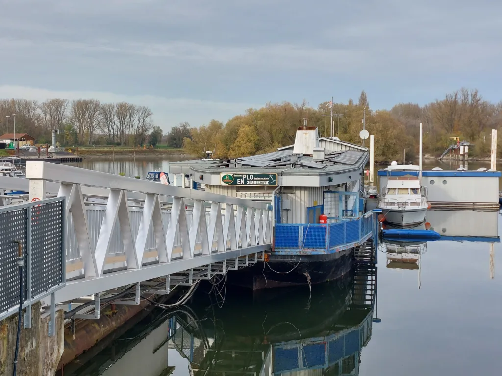 Man sieht einen Steg entlang. Am Ende ist ein Motorboot angelegt.