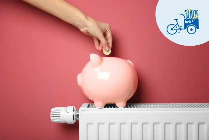 Auf dem Bild ist eine Heizung zu sehen, auf der ein rosa Sparschwein steht. Eine Frau wirft eine Münze in das Sparschwein.