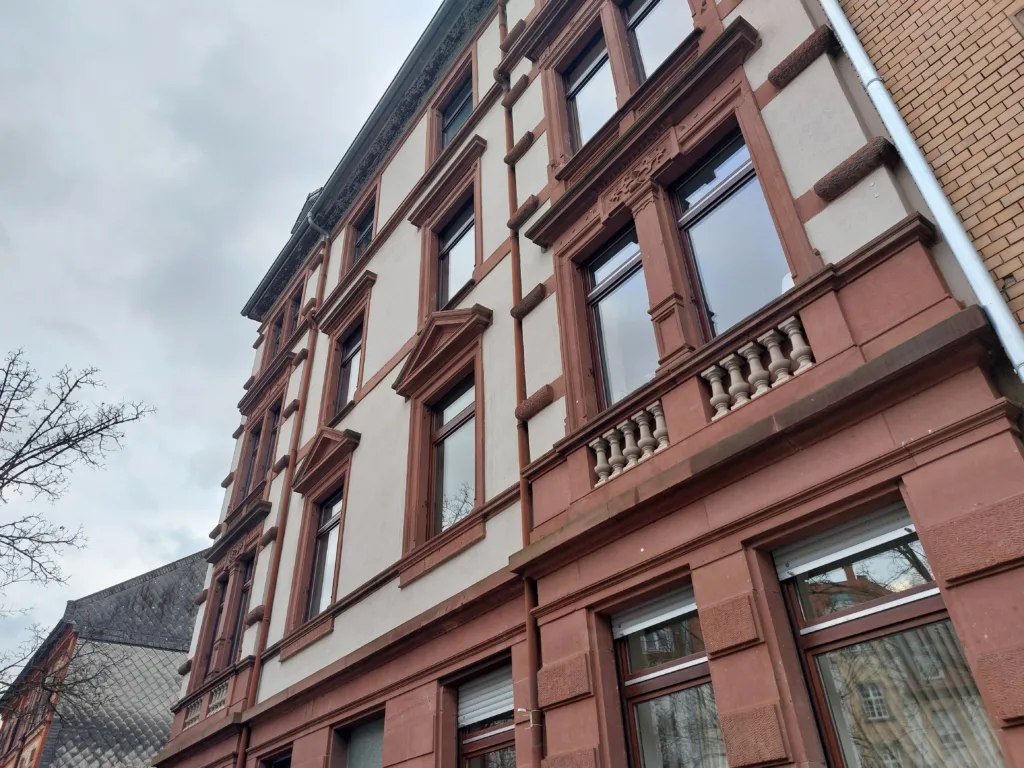 Ein Mehrfamilienhaus ist von außen zu sehen. Es handelt sich um einen Altbau in rot und beigen Farben.