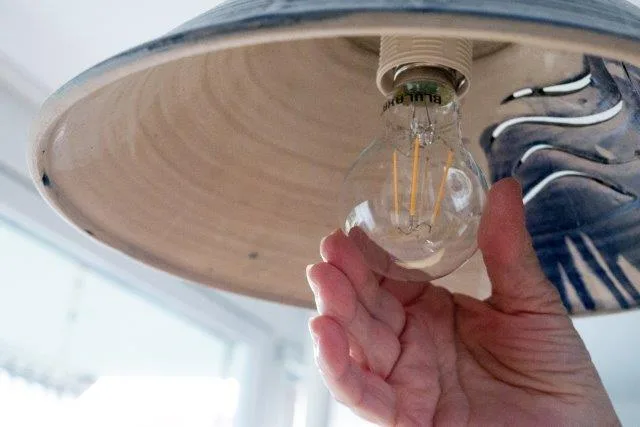 Eine Hand dreht eine LED-Birne in eine Lampenfassung.