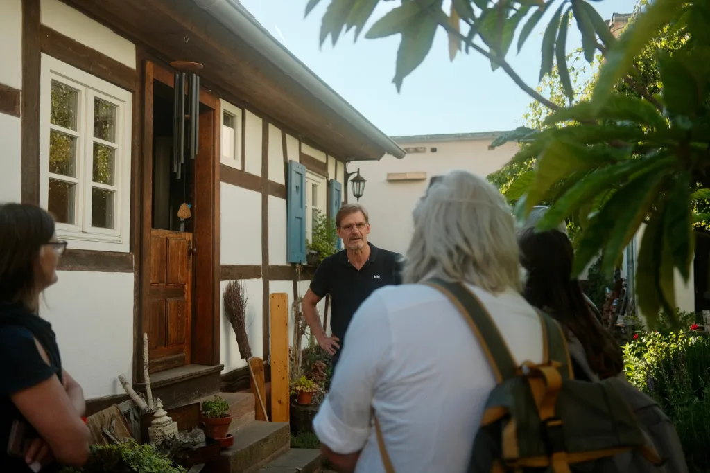 Menschen stehen vor einem Haus, das mit Photovoltaik bedeckt ist. Das Bild ist im Rahmen eines Sanierungsspaziergangs entstanden.