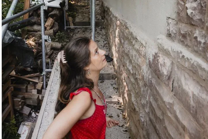 Die Hausbesitzerin Galina steht vor ihrem Haus und blickt die Fassade besorgt nach oben.
