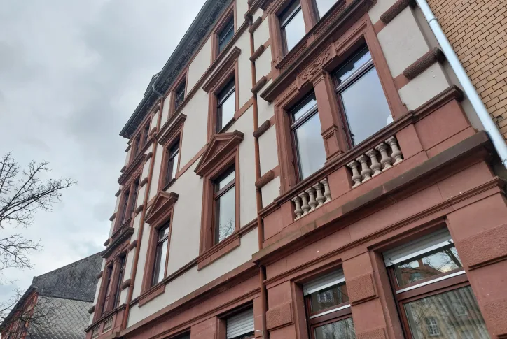 Ein Mehrfamilienhaus ist von außen zu sehen. Es handelt sich um einen Altbau in rot und beigen Farben.